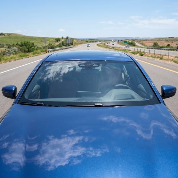 Windshield serisi şeffaf ön cam filmi uygulanmış mavi sedan, güneşli açık otoyol